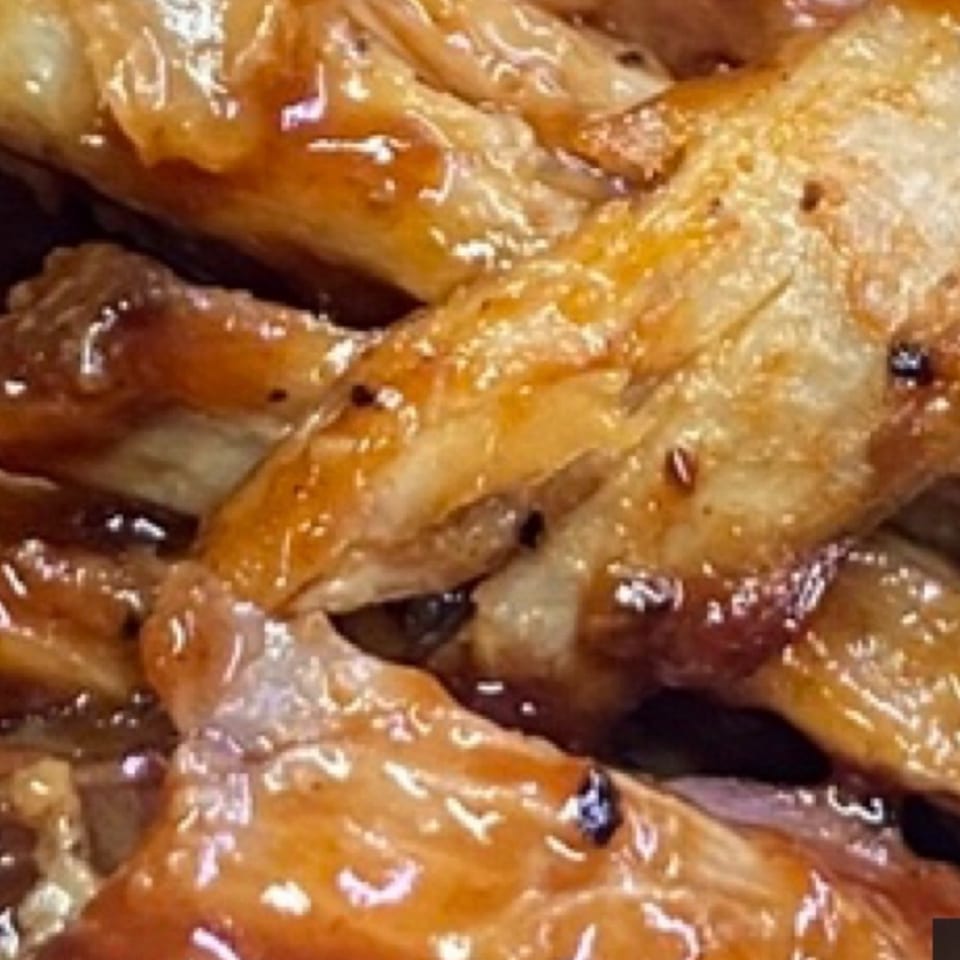 Close-up of glossy, caramelized roasted meat pieces coated in a rich brown sauce.