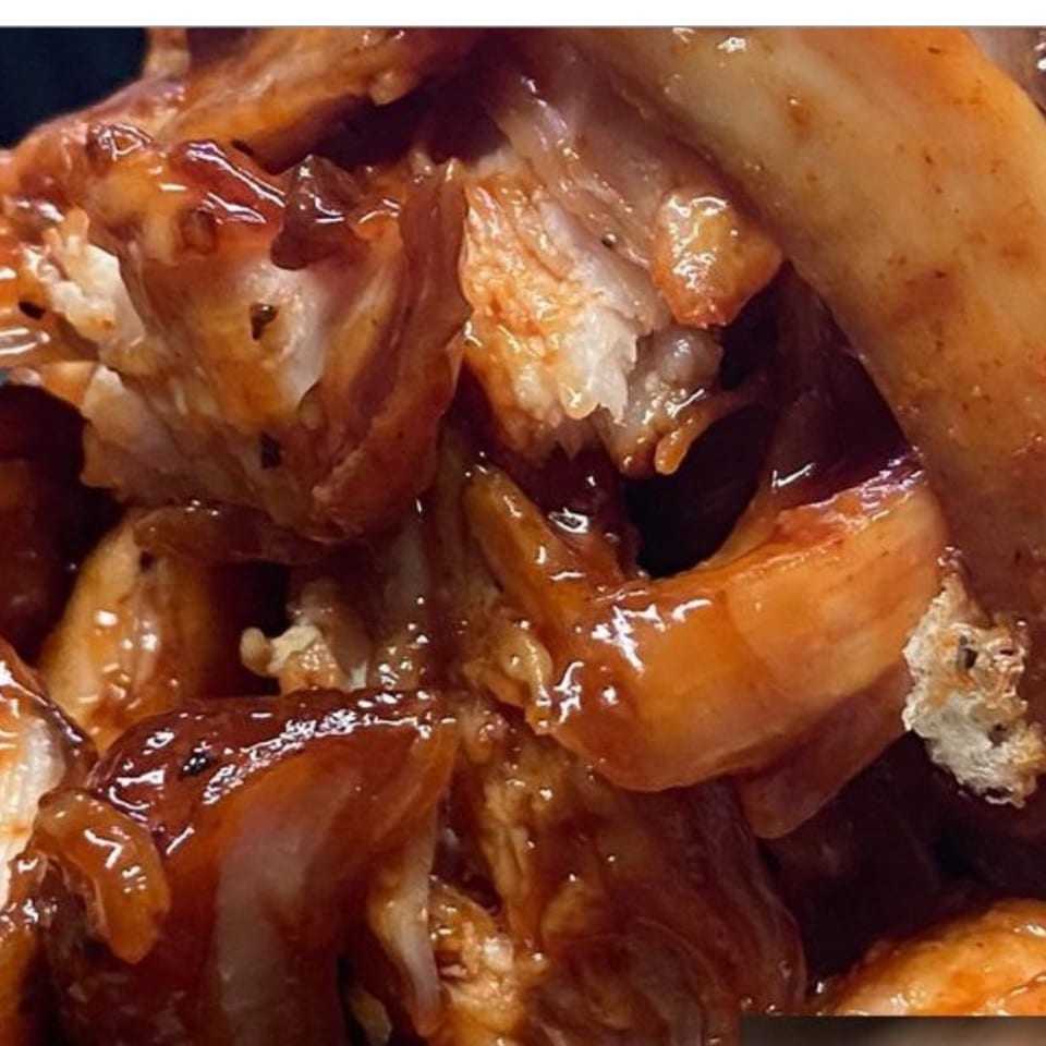 Close-up of glossy, saucy shrimp pieces arranged together, showcasing their orange shells and textured surfaces.